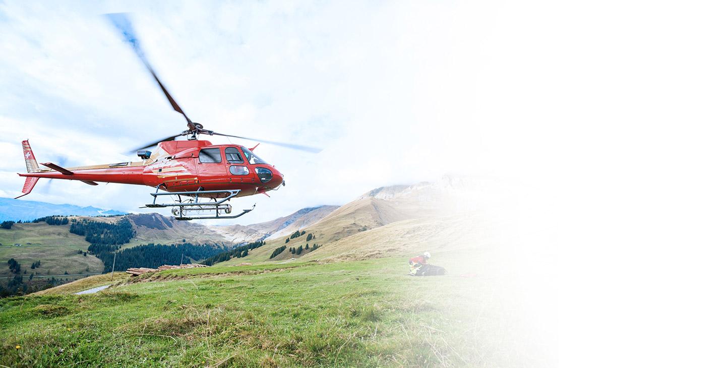 红色直升机飞过一个跪在山边草地上的人